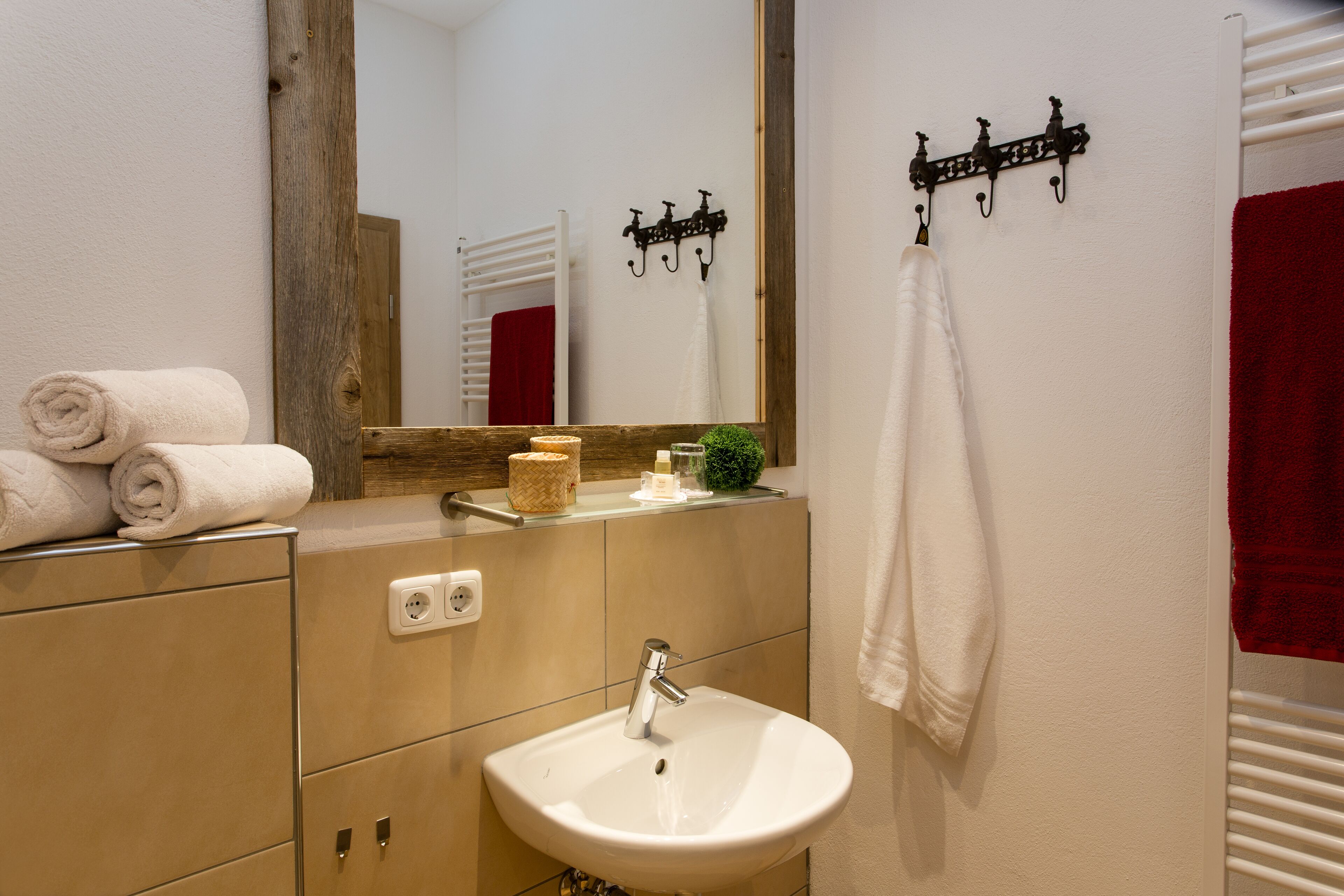Un bagno con lavandino, specchio, porta asciugamani e un armadietto in legno.