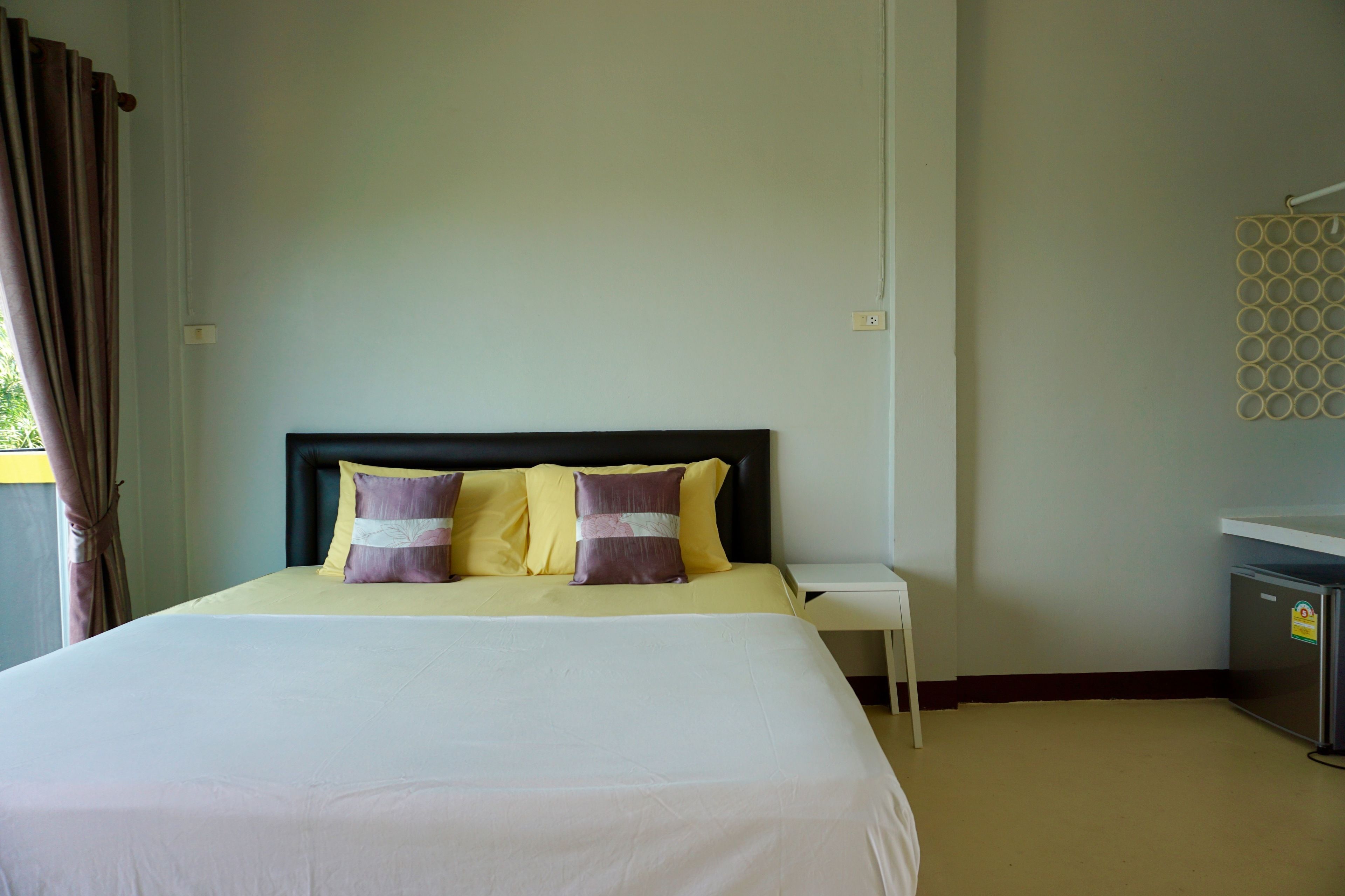 A neatly made bed with two pillows, a bedside table, and a small cabinet.