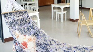 A spacious living area with a hammock, white furniture, a kitchen area with a refrigerator, and a bar counter. - Lom La Lanta Hotel (Ko Lanta)