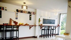 A modern kitchen with a wooden bar, bookshelves, and a chalkboard wall. - Lom La Lanta Hotel (Ko Lanta)