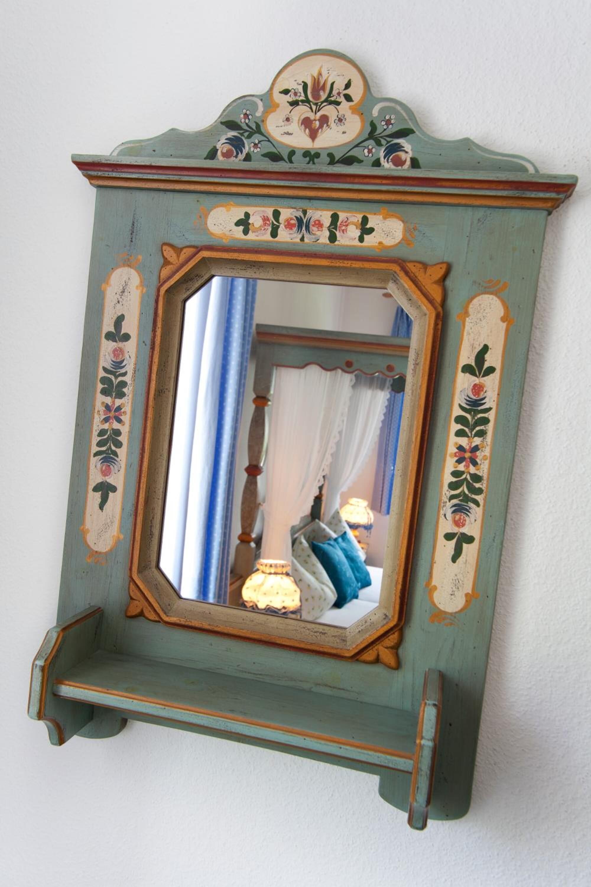 A mirror with a decorative frame, mounted on a wall.