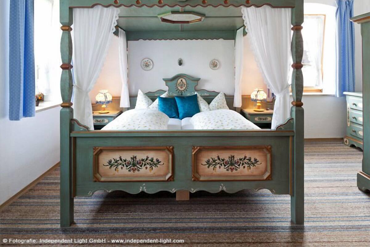 Un lit à baldaquin, deux tables de chevet et un couvre-lit à motifs floraux.