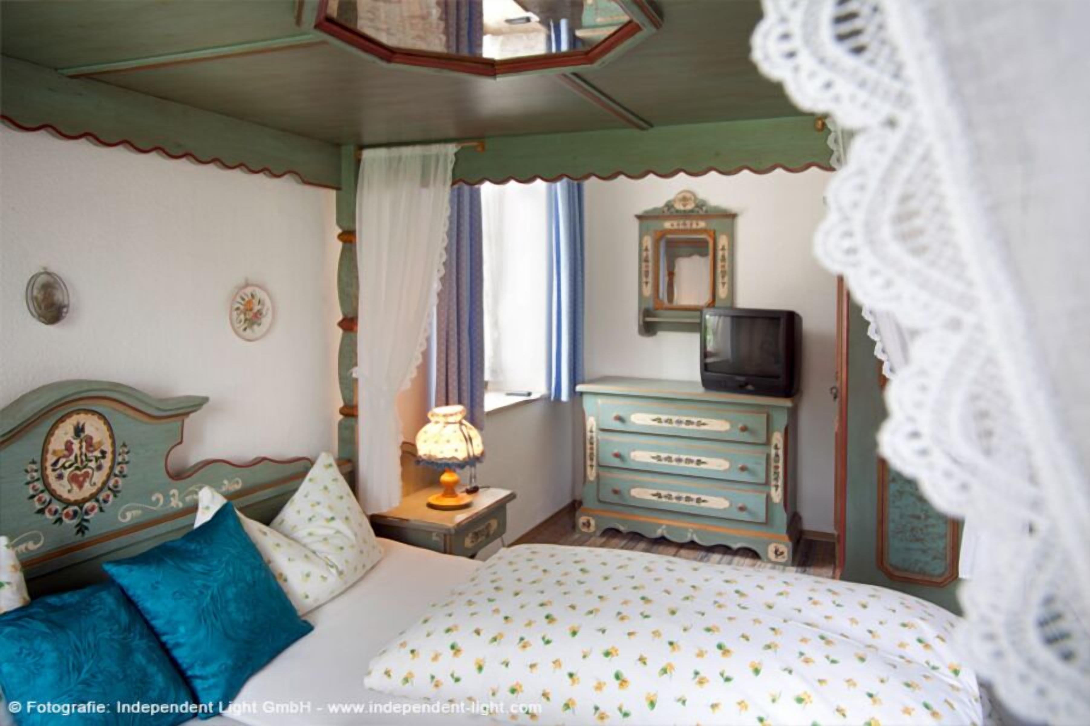 A vintage bedroom with a bed, dresser, and television.