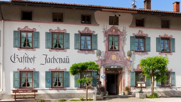 A building with multiple windows, a bench, and a sign that reads "Balthot Jachernau."