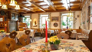 A restaurant with wooden furniture, floral tablecloths, and a red candle centerpiece.