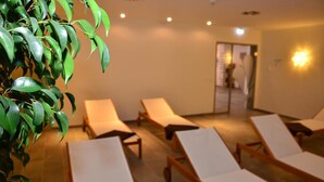 A room with several sun loungers arranged in a row, a potted plant to the left, and a door leading to another room. - Hotel Kapellenberg (Eibelstadt)