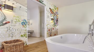 Een badkamer met een groot bad, een rieten mand en decoratieve wanddecoratie.
