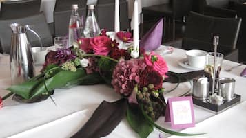 A table set for a formal event with a centerpiece of flowers, a candle, and a menu card.
