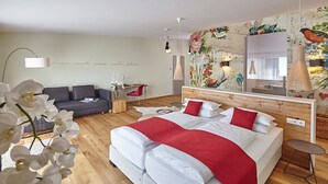A modern hotel room with a large bed, a desk, and a sofa. - Hotel Kapellenberg (Eibelstadt)