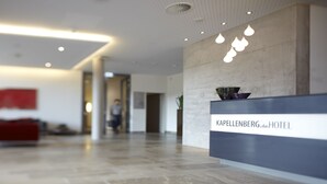 A modern hotel reception area with a reception desk labeled "Kapellenberg Hotel". - Hotel Kapellenberg (Eibelstadt)