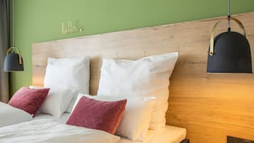 A neatly made bed with white and pink pillows, a wooden headboard, and a 'hello' sign on the wall.