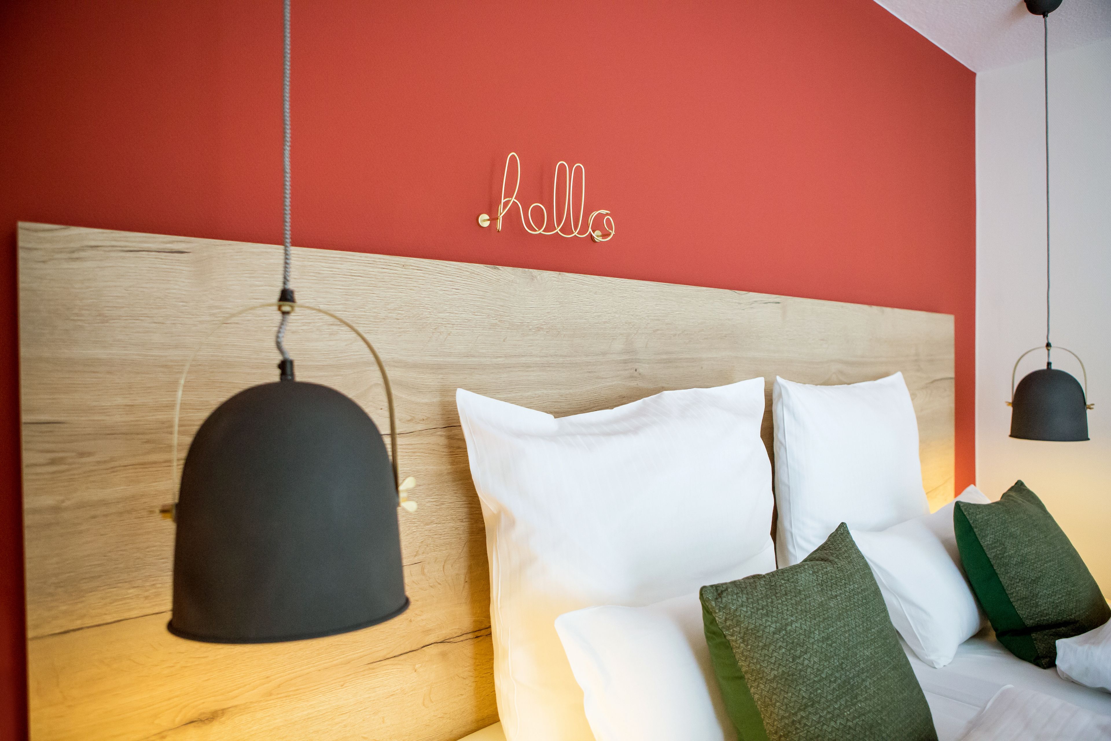 Un dormitorio moderno con cabecera de madera, ropa de cama blanca y un letrero en la pared que dice 'hello'.