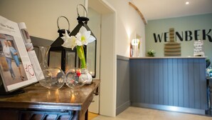 A reception desk with a magazine, a vase with flowers, and a black lantern. - Hotel, Restaurant und Weinhandel Weinbek (Fockbek)