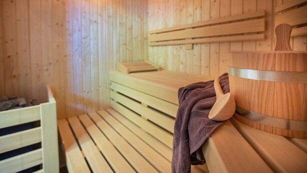 A wooden sauna room with benches and a wooden bucket. - Hotel, Restaurant und Weinhandel Weinbek (Fockbek)