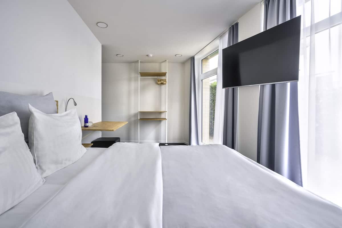 Une chambre d’hôtel moderne avec un grand lit, un bureau et une télévision.