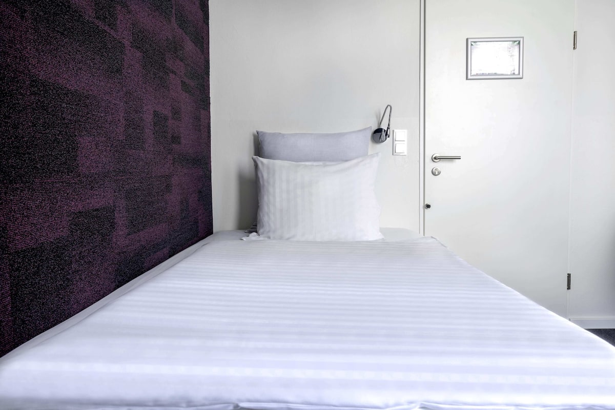 Une chambre d’hôtel avec un lit, une porte et un mur orné d’un motif texturé.