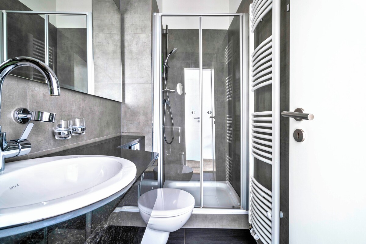 A modern bathroom with a large sink, mirror, and glass shower enclosure.