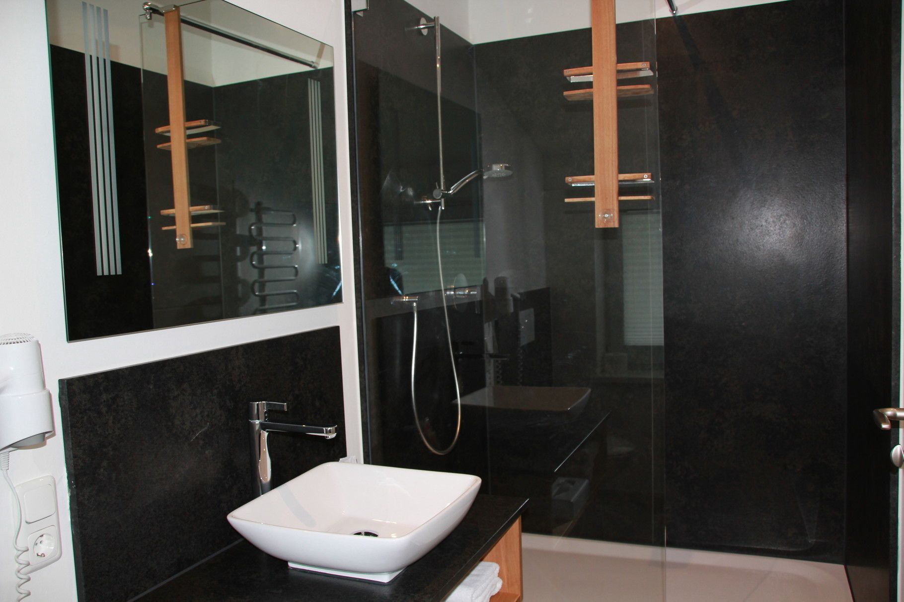 Une salle de bain moderne avec un lavabo blanc, une douche en verre et un grand miroir.