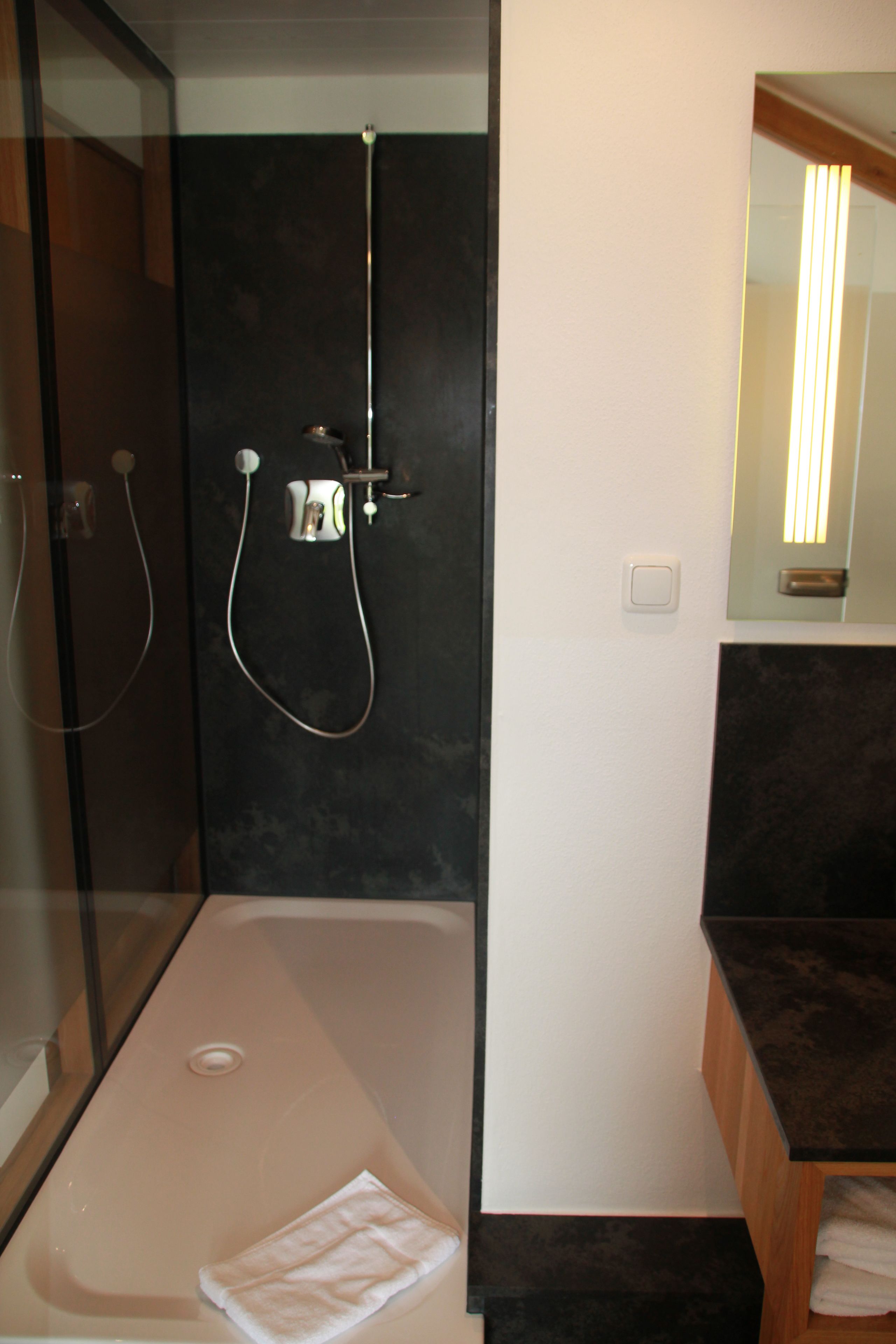 Ein modernes Badezimmer mit einer gläsernen Duschkabine, einer freistehenden Badewanne und einem Holzwaschtisch mit Spiegel.
