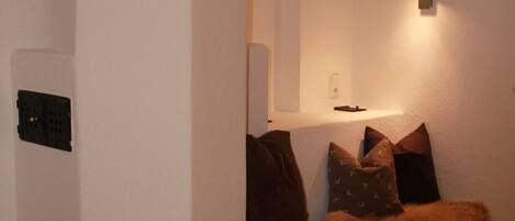 A corner room with a built-in bench, a wall-mounted light, and a power outlet.