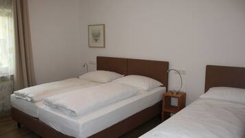 A double bed with a wooden headboard, a bedside table with a lamp, and a framed picture on the wall.