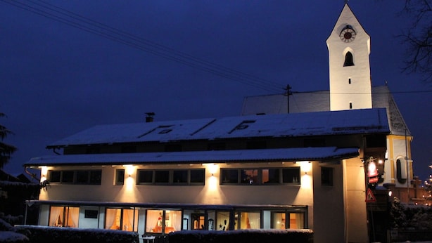 Ein Gebäude mit einem Glockenturm, vielen Fenstern und einem mit Schnee bedeckten Dach.