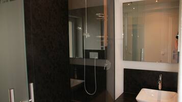 A modern bathroom with a glass-enclosed shower, a white sink, and a large mirror.