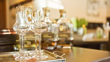 A bar area with three clear stemmed glasses on a tray, and bottles of liquor in the background.