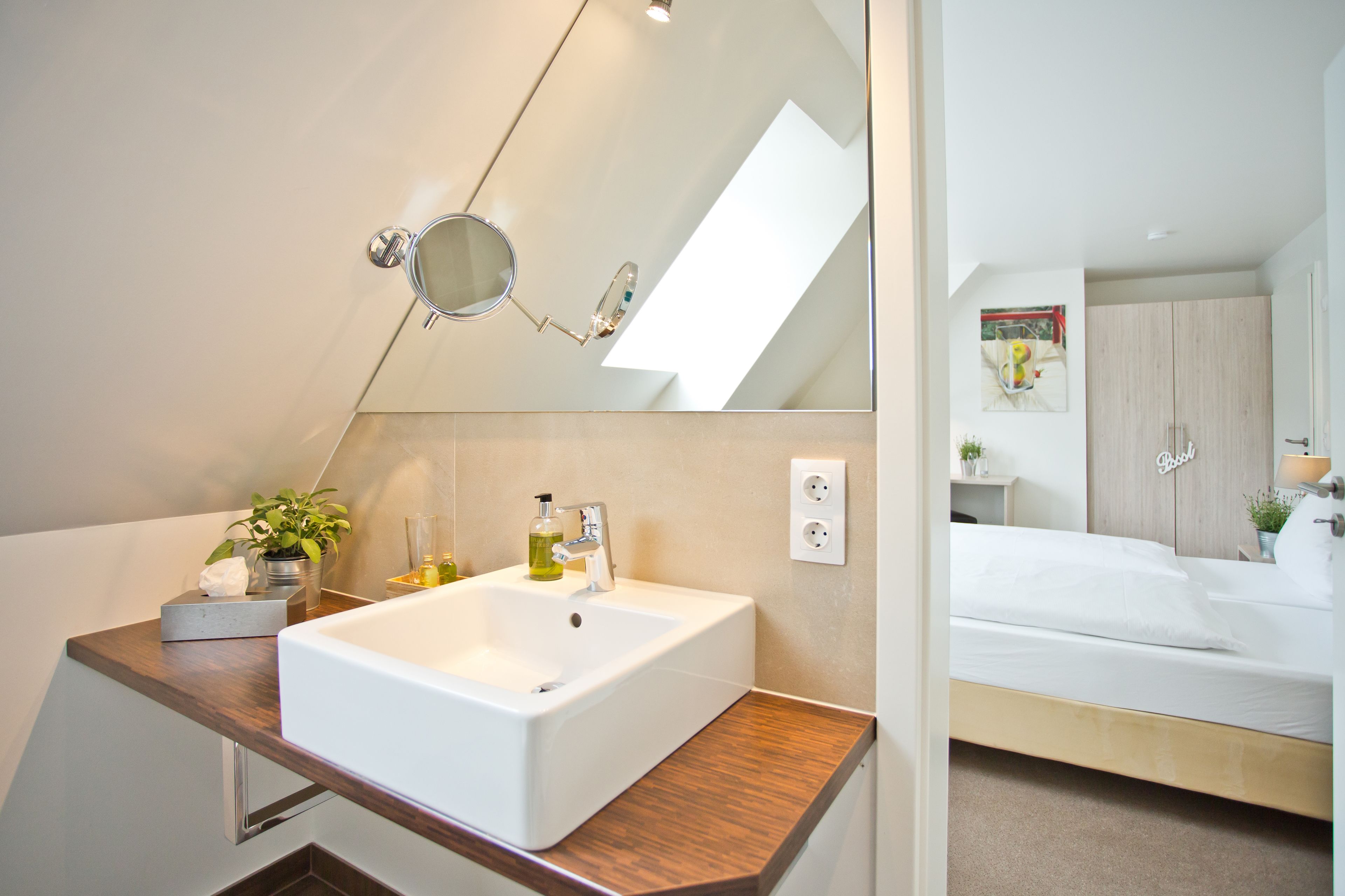 A modern bathroom with a large mirror, a white sink, and a wooden countertop.
