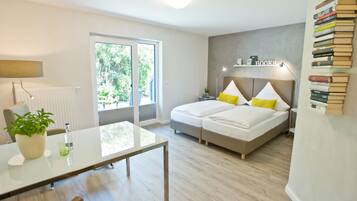 Un dormitorio moderno con cama, mesita de noche, lámpara y una estantería llena de libros.