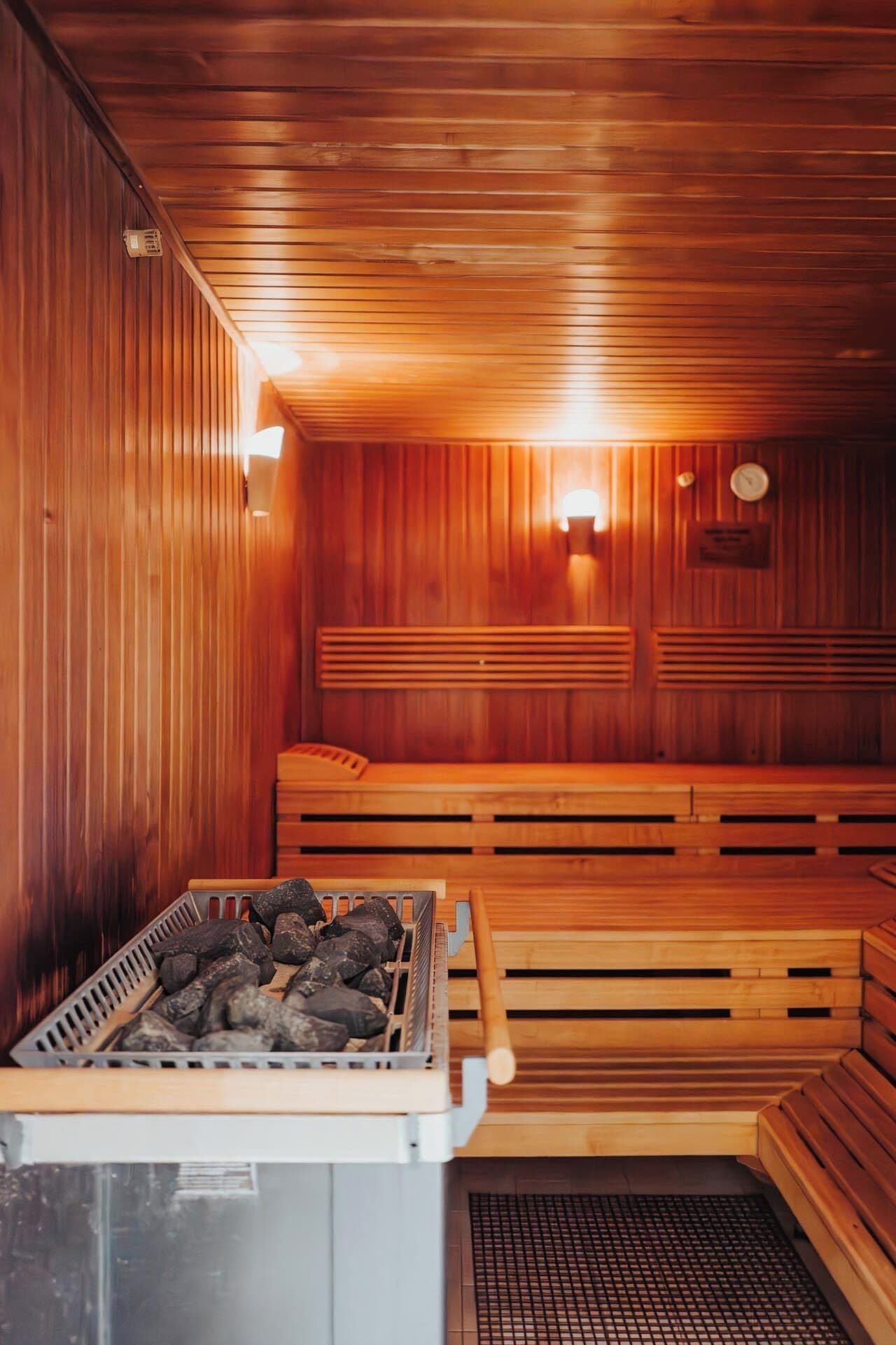 Una sala de sauna con bancos de madera y una parrilla de carbón.