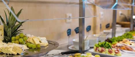 Un bufé con diversos alimentos, incluyendo queso, frutas y ensaladas.