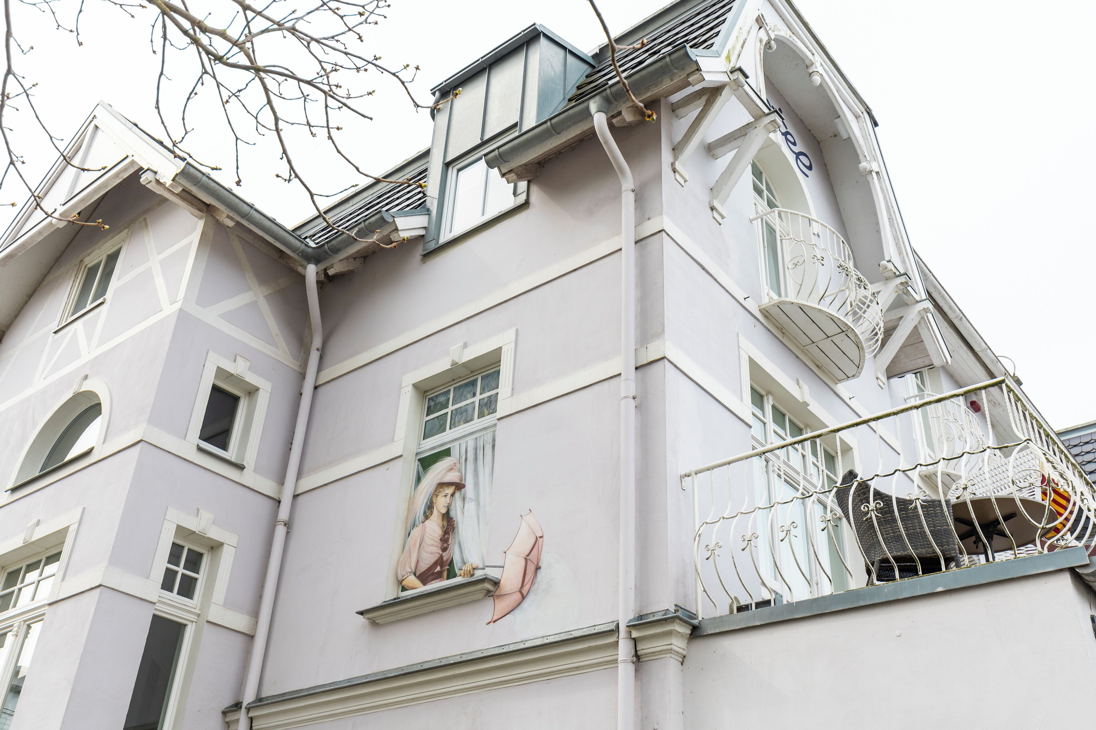 Un immeuble doté de nombreuses fenêtres, d’un balcon avec une rambarde en métal et d’une fresque murale.