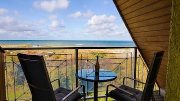 Ein Balkon mit zwei Stühlen und einem Tisch, mit Blick auf Strand und Meer.