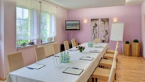 A conference room with a long table, chairs, a whiteboard, and a TV screen. - Seehotel Düne (Graal Mueritz)