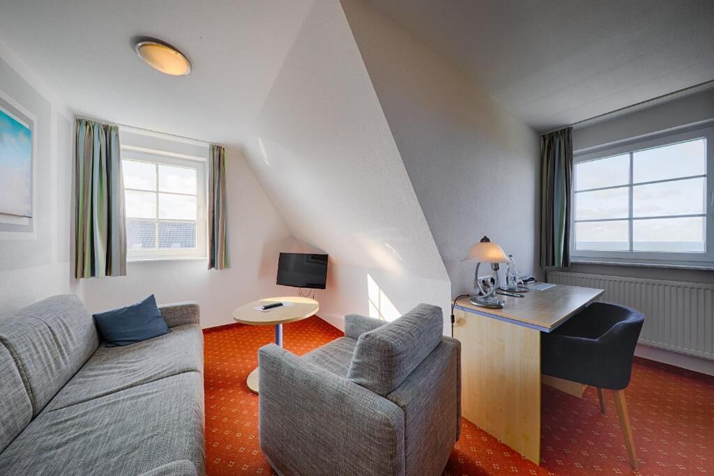 Una habitación de hotel moderna con techo curvo, un sofá, un escritorio y una silla.