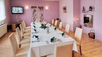 Uma sala de jantar com uma mesa comprida posta para refeição, rodeada por cadeiras.