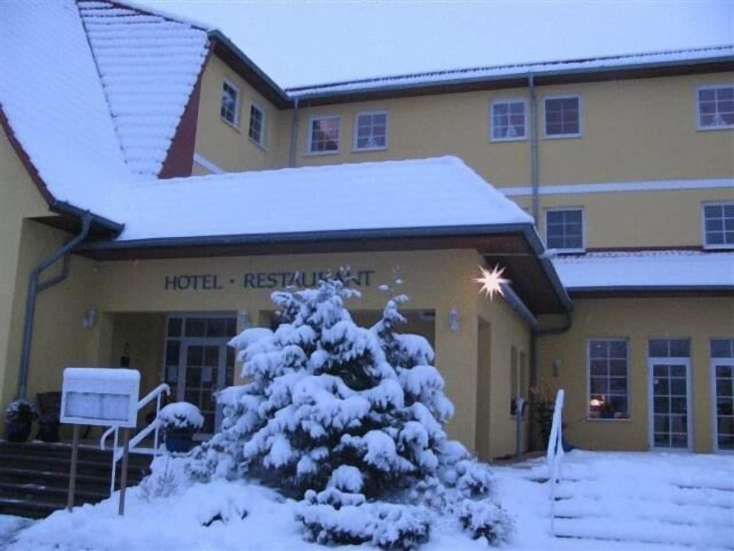Un hotel con entrada cubierta de nieve y un letrero que dice 'HOTEL RESTAURANT'.