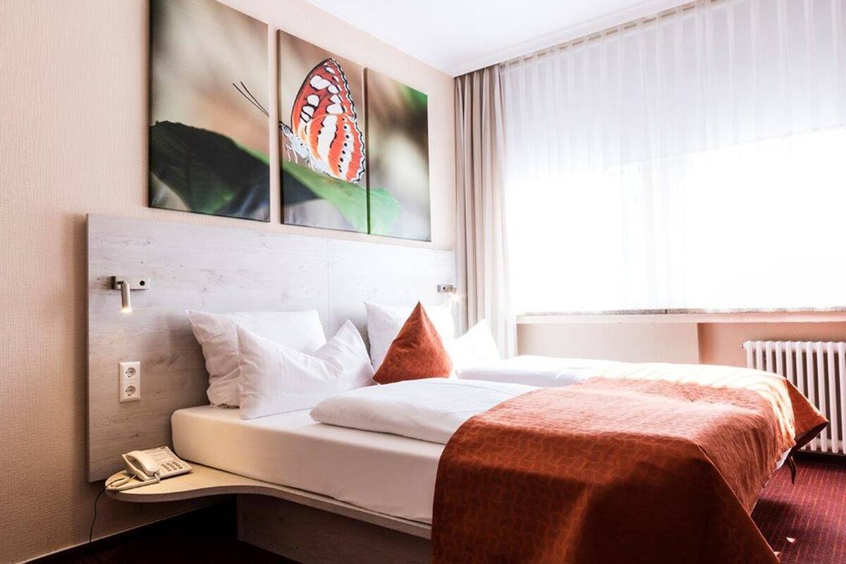 Habitación de hotel con cama, teléfono y obras de arte en la pared.