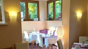 A dining area with tables set for two, featuring white tablecloths and a purple carpet. - Elisabetha (Hannover)