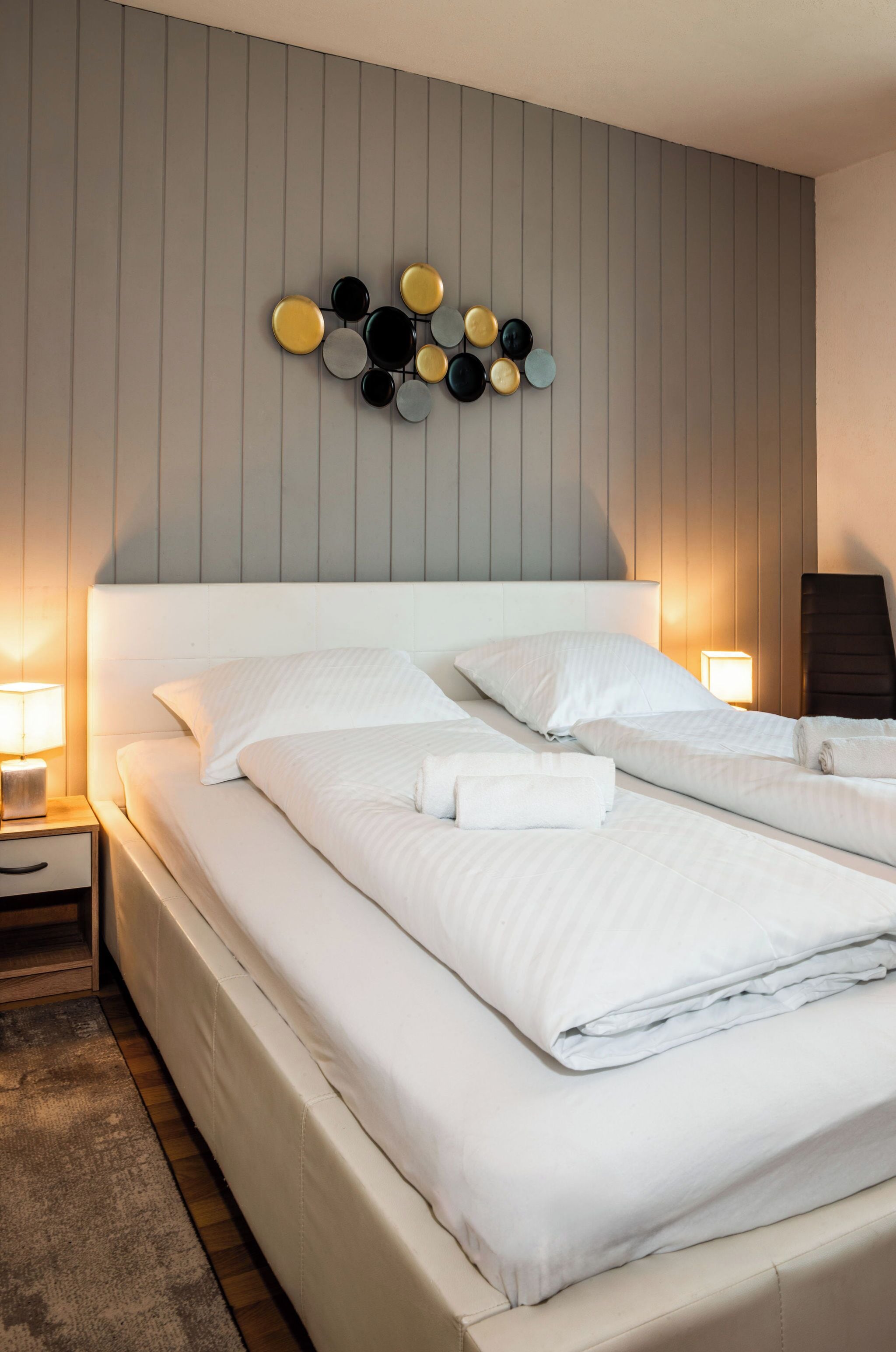 A hotel room with two beds, a wall-mounted circular decoration, and bedside lamps.