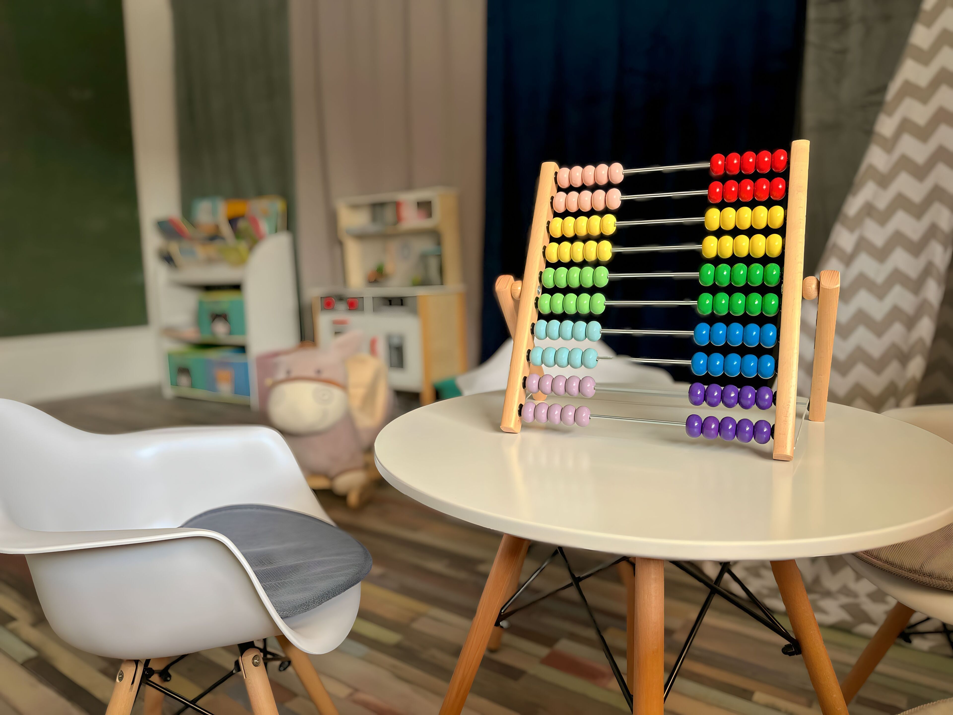 A room with a round table, a white chair, and a colorful abacus.