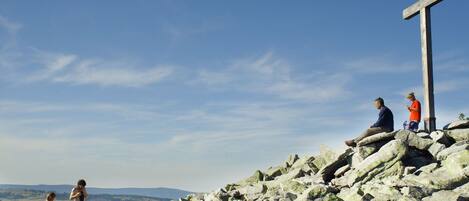 A cross on a rocky hill with a clear sky.