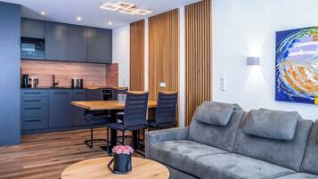 A modern living room with a grey sofa, wooden coffee table, and a dining area with a wooden table and chairs.