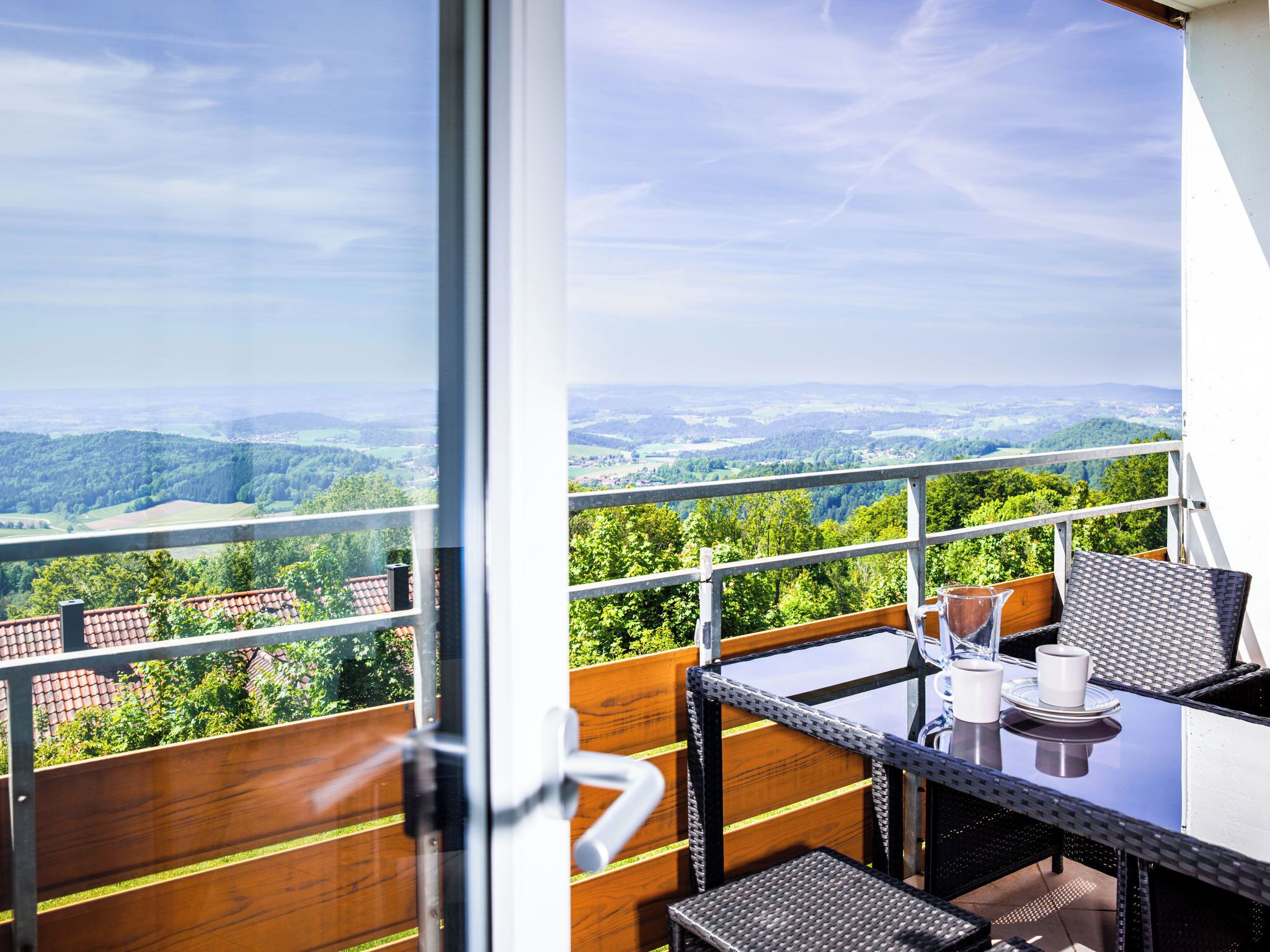 Un balcon avec une table et des chaises, donnant sur un paysage pittoresque.