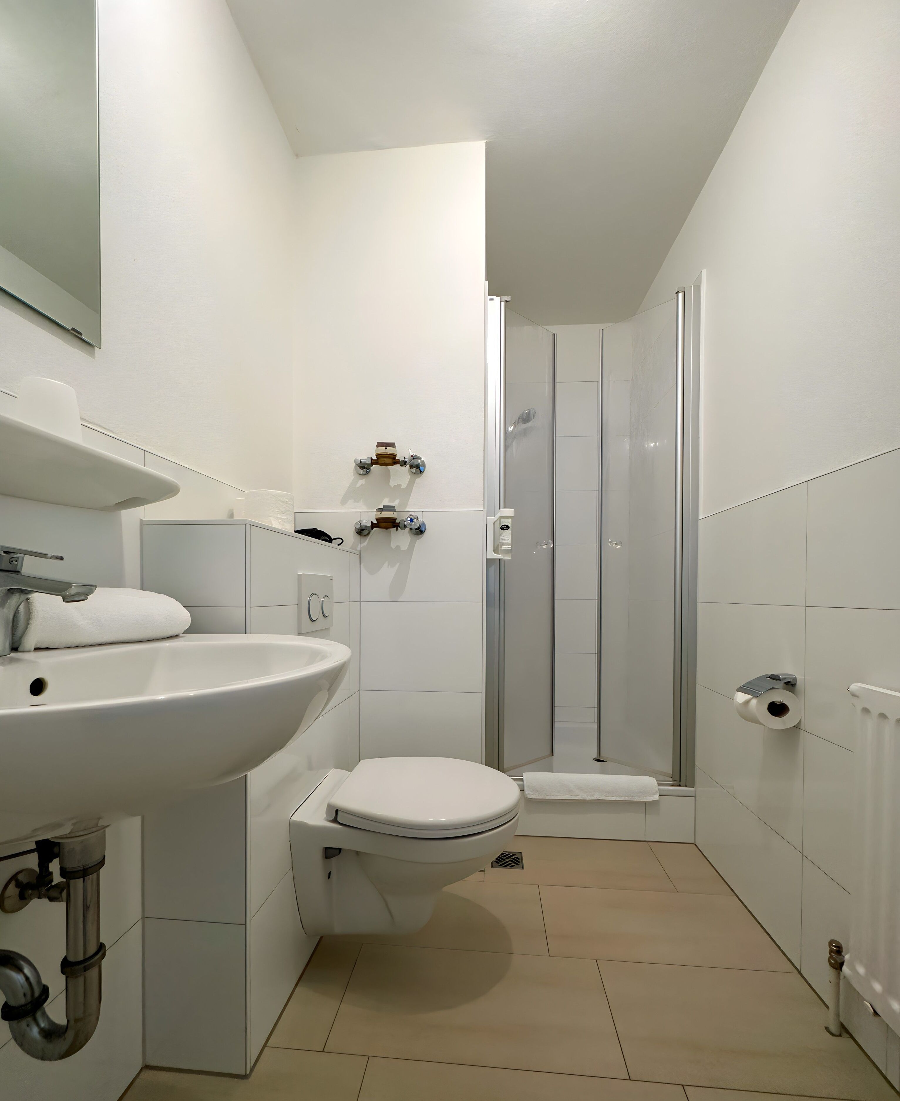 A modern bathroom with a sink, toilet, and glass shower enclosure.