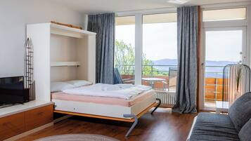 Un dormitorio con cama, televisión, sofá y balcón con vistas.