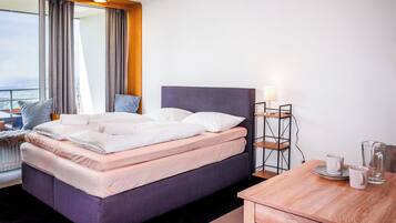 Une chambre d’hôtel avec un lit, une table de chevet avec une lampe, une vue sur la ville et une fenêtre avec des rideaux.