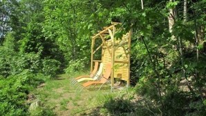A wooden play structure with slides in a wooded area. - Greizer Kammhütte Gaststätte & Pension (Klingenthal)