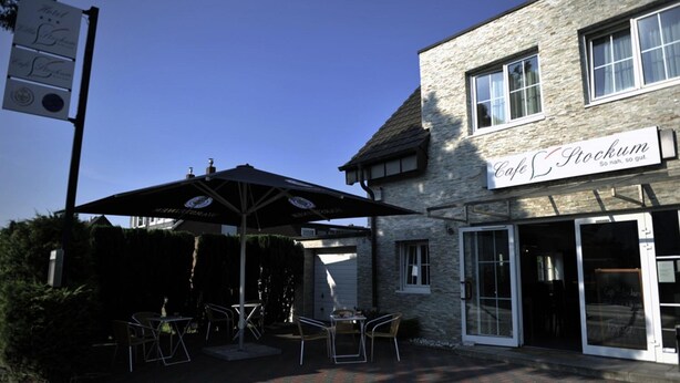 A cafe with outdoor seating, a stone building, and a signboard. - Hotel Villa Stockum (Düsseldorf)